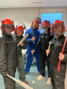 Groep mensen in veiligheidsuitrusting poserend met knuppels, breekijzer en golfclub