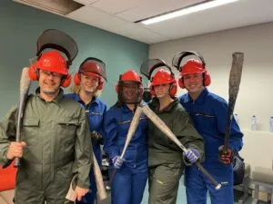 Rage room groep in volledige veiligheidsuitrusting met knuppels in de hand, samen lachend