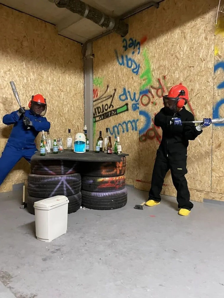 Twee mensen die hun wapens richten op flessen en elektronica in de smash room